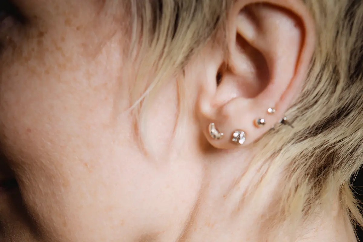 Se muestra una oreja con varios perforaciones y pendientes