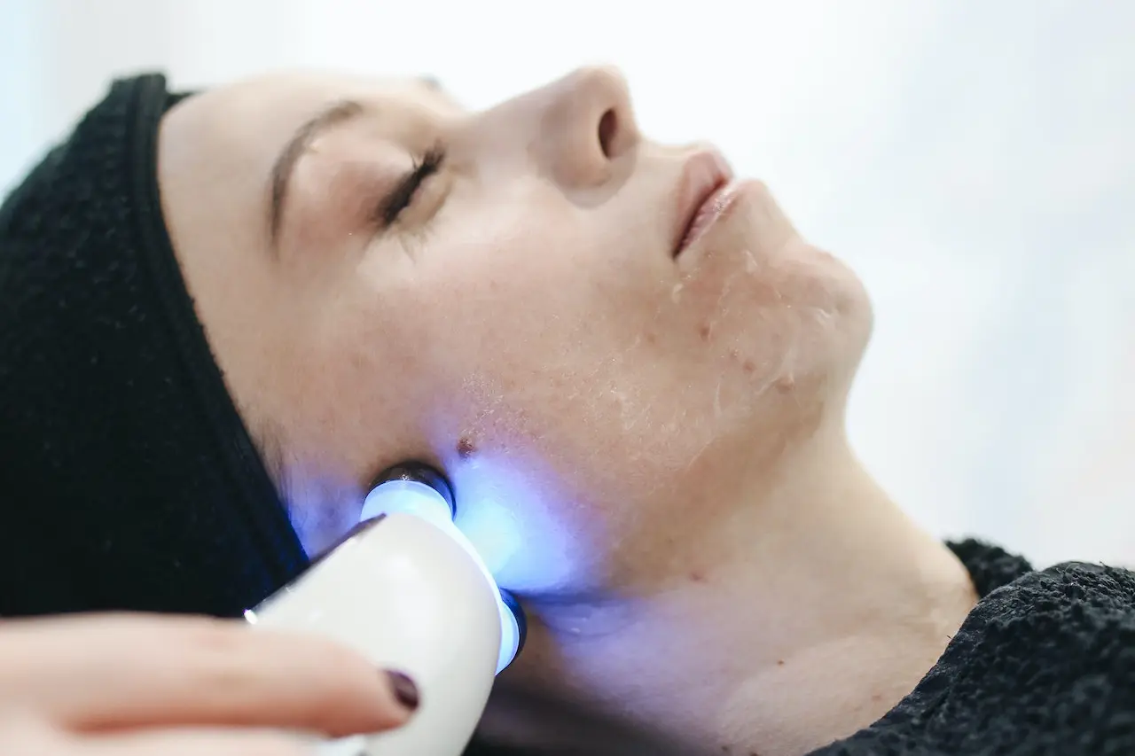 Se muestra la cara de una mujer con una máquina de rayos ultravioleta
